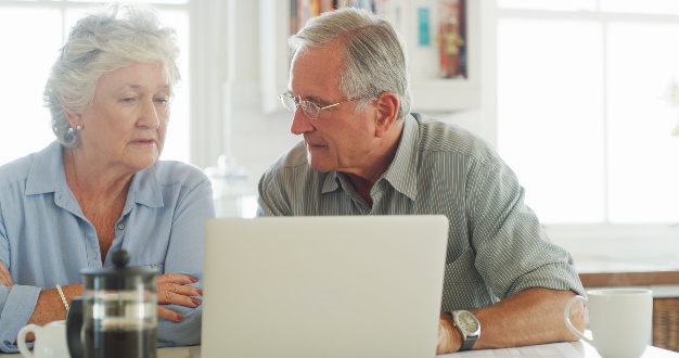 Elderly couple using a laptop together.