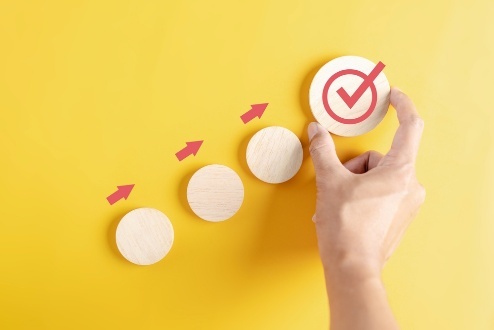 Hand arranging wooden blocks with red checkmark.