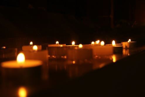 Glowing tea light candles on dark surface