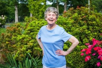 Smiling elderly woman standing in flower garden