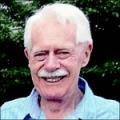 Elderly man smiling outdoors in a garden.