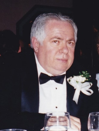 Man in tuxedo with boutonniere at event.