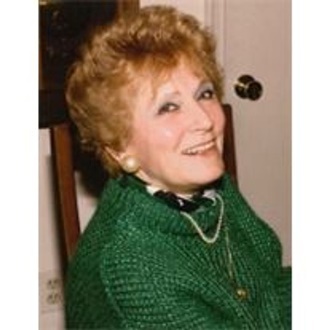 Smiling woman in green sweater, seated indoors.