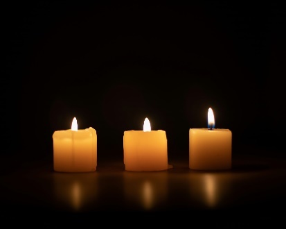 Three lit candles in the dark setting.