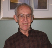 Smiling elderly man in glasses and plaid.