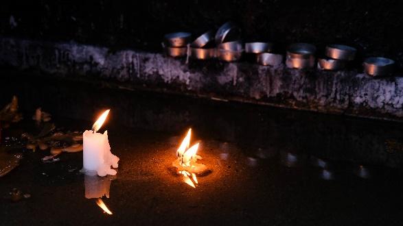Two lit candles reflected on water at night