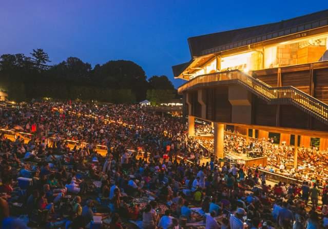 Crowded outdoor amphitheater concert at dusk