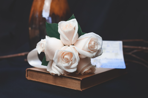 White roses on a book with envelope.