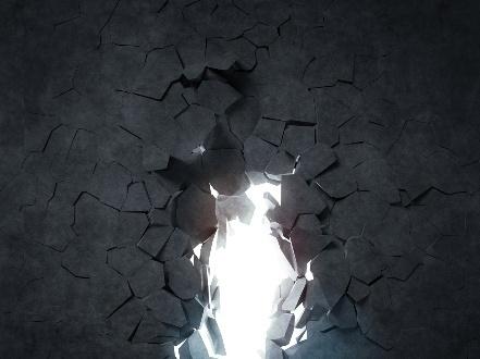 Bright light shining through cracked concrete wall