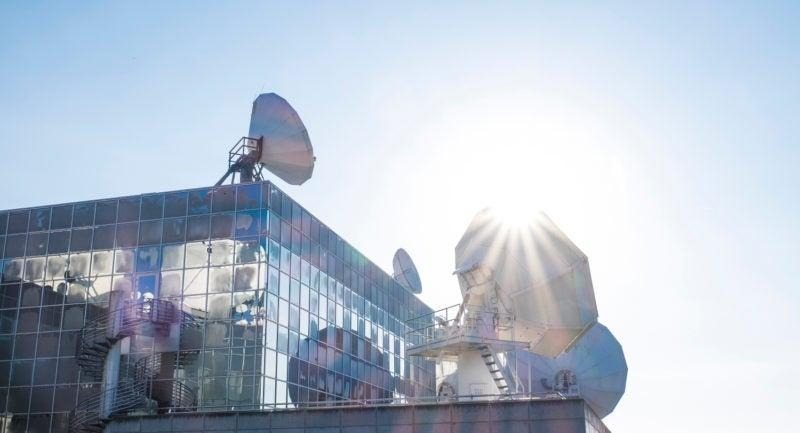 Rooftop satellite dishes on reflective glass building