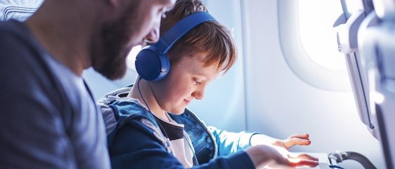 Child wearing headphones on airplane seat