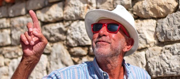 Elderly man in hat pointing at sky