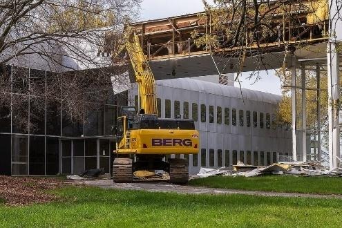 Excavator demolishing elevated walkway at office complex