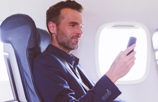 Male passenger seated on airplane using smartphone