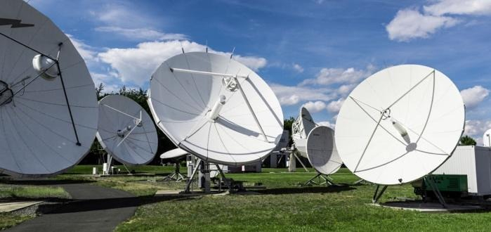 Array of white satellite dishes under blue sky